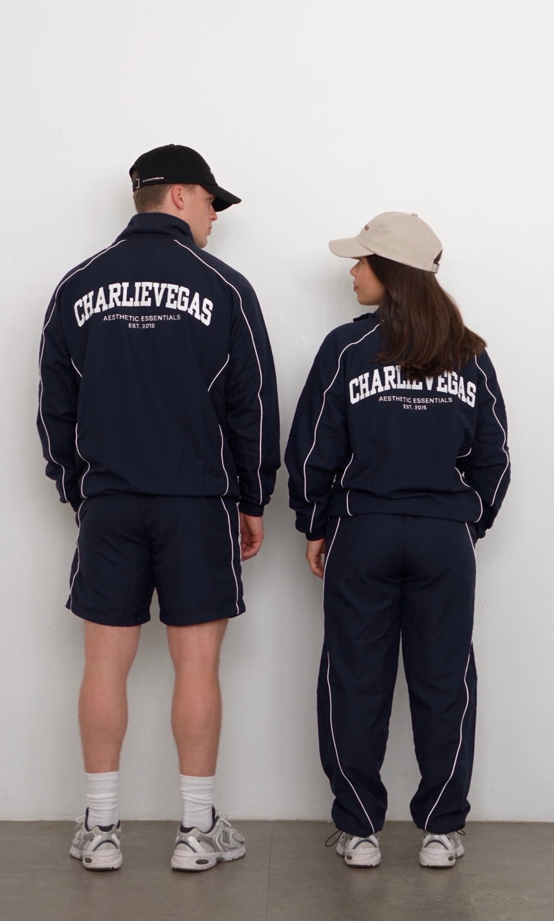 Two models wearing the navy Aesthetics Club tracksuit, back view